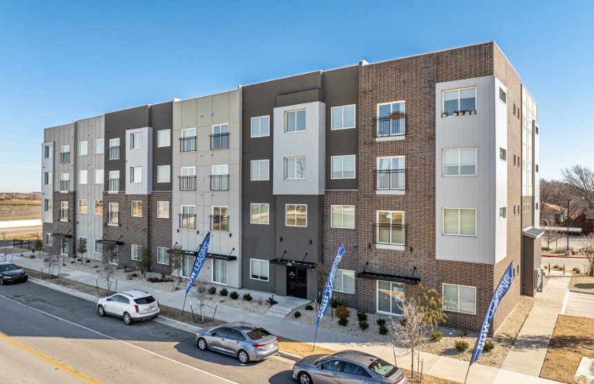 A modern apartment building with cars parked in front.